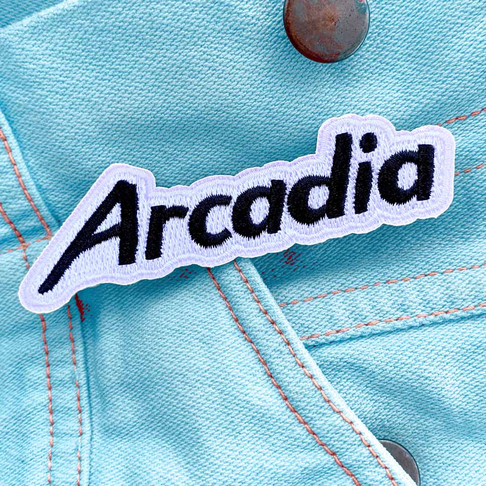 Arcadia Deluxe album art: a fabric patch reading "ARCADIA" over a baby blue denim jacket